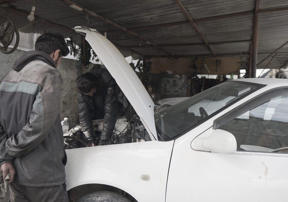 two mechanics fixing a white vehicle